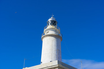 Fototapeta na wymiar lighthouse next to the Mediterranean Sea, blue sky without clouds with calm waters. serves to warn ships of the presence of rocks