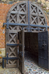 Medieval castle wooden door with massive iron hinges. Door is open.