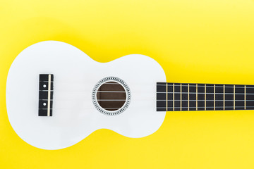 White ukulele on a yellow background and with a place for text. Musical concept. Flat Lay