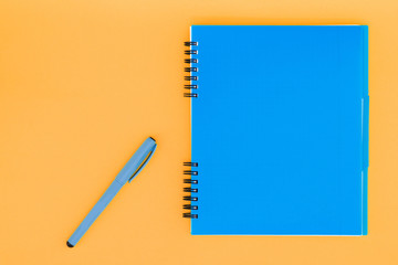 A blue notebook with a handle on the orange background. Flat Lay Template. Place for text.