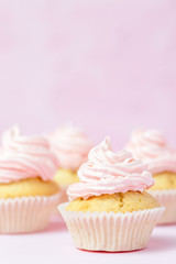 Cupcake decorated with pink buttercream on pastel pink background. Sweet beautiful cake. Vertical banner, greeting card for birthday, wedding, women's day. Close up photography. Selective focus