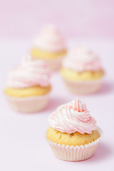Cupcake decorated with pink buttercream on pastel pink background. Sweet beautiful cake. Vertical banner, greeting card for birthday, wedding, women's day. Close up photography. Selective focus