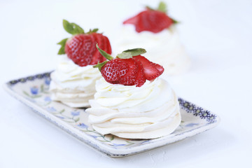 Three homemade mini cakes with meringue (pavlova) and cream cheese with strawberries. Selective focus.