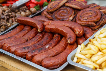 Fresh, hot sausages cooked on the grill, outdoors, on the coals.