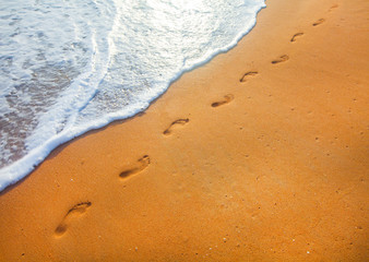 beach, wave and footprints at sunset time