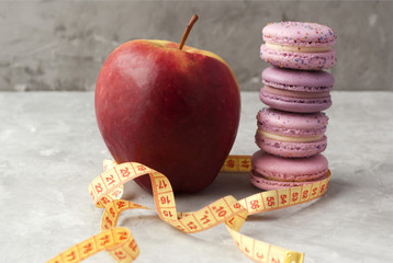 Close-up view of apple, macarons and measuring tape. Concept of nutrition