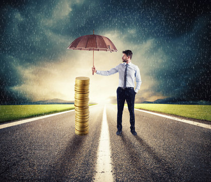 Businessman protects his money savings with umbrella. concept of insurance and money protection