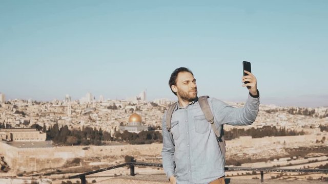 Happy man takes selfie in old town Jerusalem. Bearded local male smiles happy, taking photos. Perfect Israel panorama 4K