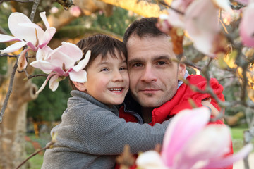 padre e hijo abrazados entre las flores de un magnolio