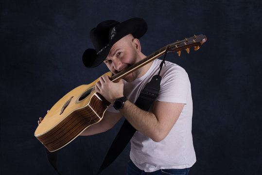 The man's portrait in a cowboy's hat with guitar.