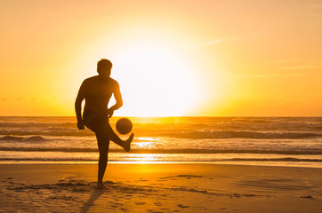 Great concept of soccer, man playing soccer on the beach in golden hour, sunset. Making keepie uppie. - Powered by Adobe