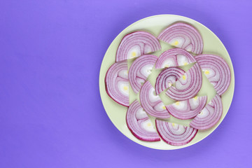 Purple onions on a green plate, onions on the ultraviolet background, sliced onions laid out on a plate, vegetables, pop art, minimalism, vegetarian product, vitamins, healthy food