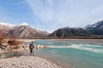 Fototapeta na wymiar Man hiker on shore of river looking the mountains.