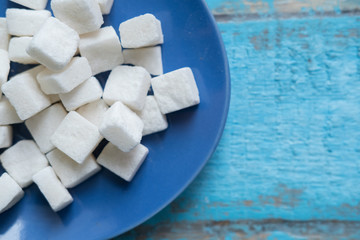pressed sugar cubes sugar refined in a blue plate standing on a textured wooden surface