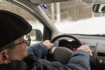 An elderly man is sitting behind the wheel of a car, traveling, active way of life