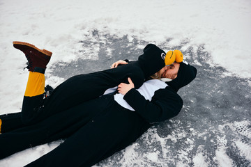 Young couple in the penguin costumes are have fun on snow. Happy Loving Couple