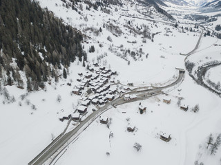 Obraz na płótnie Canvas Aerial view of small houses in snow covered landscape in Swiss alps in Canton of Wallis