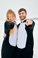 Young couple in the penguin costumes are have fun on snow. Happy Loving Couple