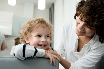 Portrait of young mother playing with cute little son smiling happily enjoying weekend at home, copy space