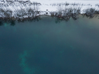 Aerial view of lake in winter with snow covered border