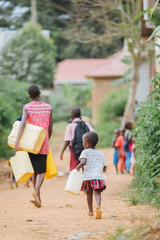 Mother and child carrying water cans in Uganda africa