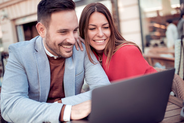 Positive young couple using laptop