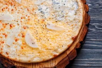 Appetizing quattro formaggi cheese pizza with pear served on wood
