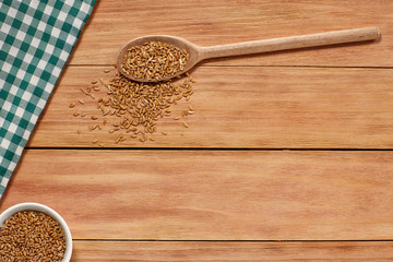 Healthy grain food and seeds in a wooden spoon on wood background with a Table Cloth. Top View. Copy Space.