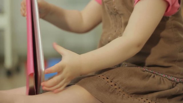 A little girl is watching cartoons in an electronic tablet