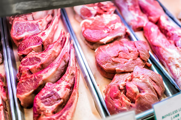 Pink red raw beef meat lamb on shanks, bone-in bone in store display, trays for sale, boneless sign fatty