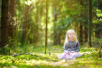 Fototapeta na wymiar Adorable little girl picking the first flowers of spring in the woods on beautiful sunny spring day