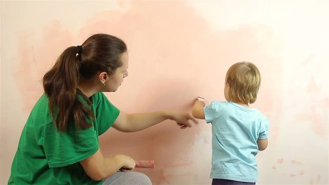 Happy little baby with mom painting wall