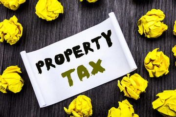 Writing text showing Property Tax. Business concept for Estate Income Taxation Written on sticky note notepad note notebook book wooden background with yellow sticky folded.