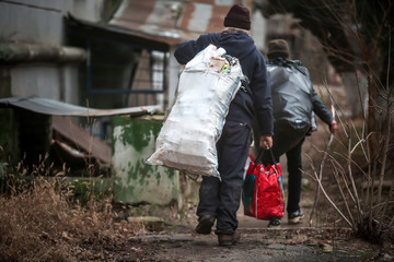 Poor people with bags of garbage outdoors