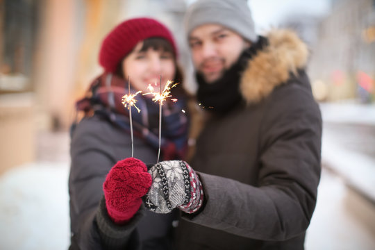 Young loving couple holding sparklers outdoors on winter day