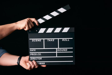 Hands with a movie clapperboard isolated on black background with copy space, close-up. Wooden...