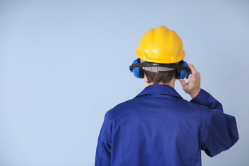 Male worker with headphones on grey background. Hearing protection equipment