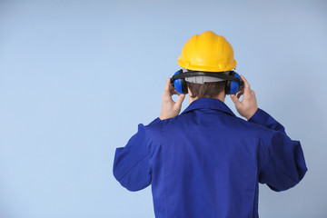 Male worker with headphones on grey background. Hearing protection equipment