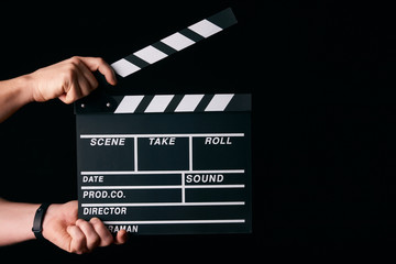 Hands with a movie clapperboard isolated on black background with copy space, close-up. Wooden...