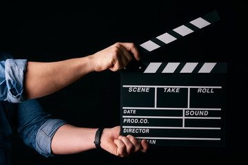 A movie production clapper board. Hands with a movie clapperboard on black background with copy...