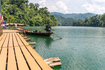 Fototapeta na wymiar Pier from the raft houses and national park ranger station Klong Pae. The long-tail boat is mooring in front