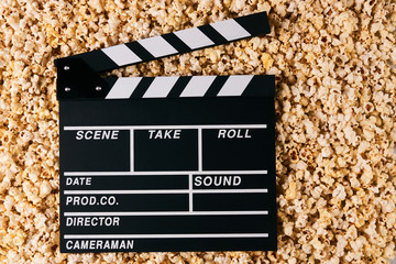 Movie clapper board and pop corn on background with copy space, top view. Movie time concept,...