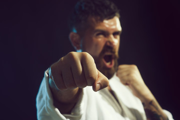 Strong arms and clenched fists. Portrait of screaming karate master instructor. Selective focus on fist. Brutal bearded man dressed in kimono practicing aikido. © Svitlana