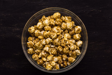 Sweet popcorn on the black background. Popcorn in the bolw. Snack for the movies. Cinema set.