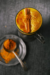 Turmeric latte or golden milk with cinnamon stick and spice mix