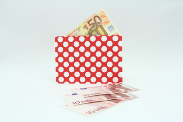 Banknoty EURO w czerwonej kopercie w białe kropki - obrazy, fototapety, plakaty