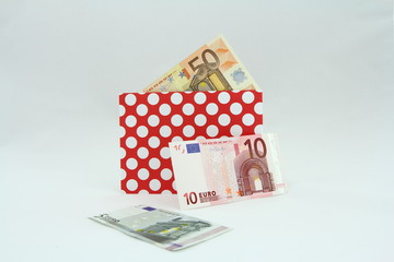 Banknoty EURO w czerwonej kopercie w białe kropki - obrazy, fototapety, plakaty
