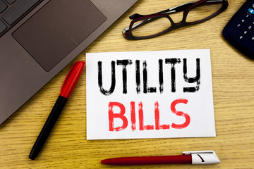 Conceptual hand writing text showing Utility Bills. Business concept for Money Bill Payment written on paper, wooden background in office with copy space, marker pen and glasses