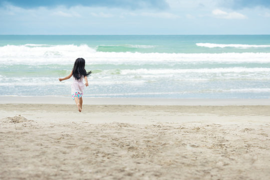 Little children girl with white dress running on a beach