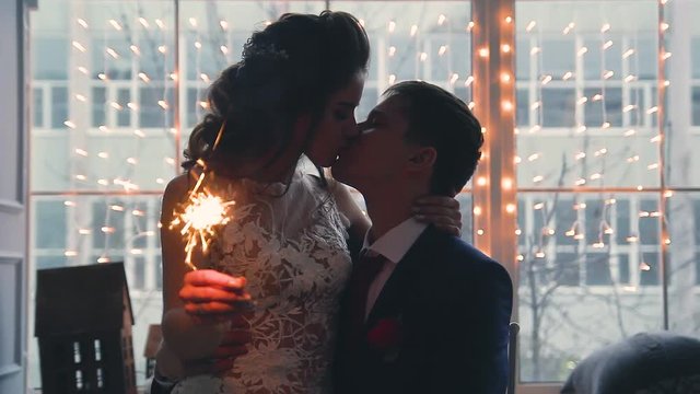 Beautiful young loving wedding couple in new year interior with Bengali lights